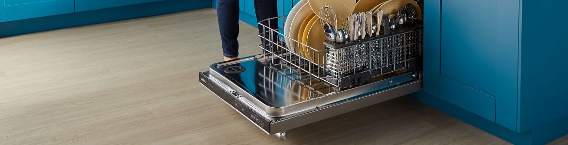 Une personne qui remplit le panier inférieur d'un lave-vaisselle.