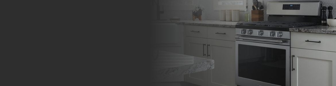 A Maytag Oven surrounded by cabinets and cupboards. On the counters are a container of kitchen utensils and salt and pepper shakers.