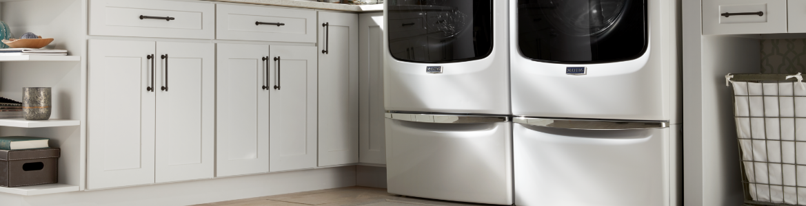 A laundry room featuring a front load washer and dryer on pedestals.