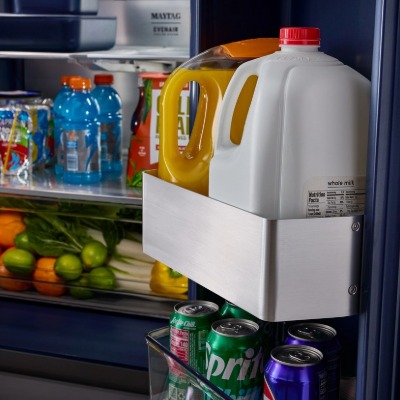 Porte de réfrigérateur ouverte avec du lait et du jus dans les compartiments de porte grand format