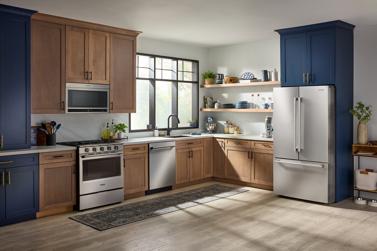 Réfrigérateur à portes françaises en acier inoxydable Maytag® dans une cuisine aux armoires brunes et bleu marine
