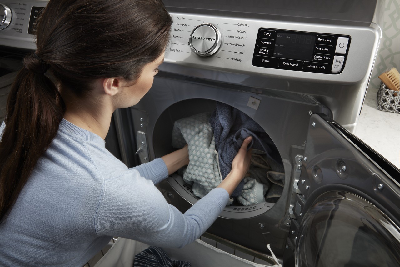 Une femme retire des vêtements d’une laveuse Maytag