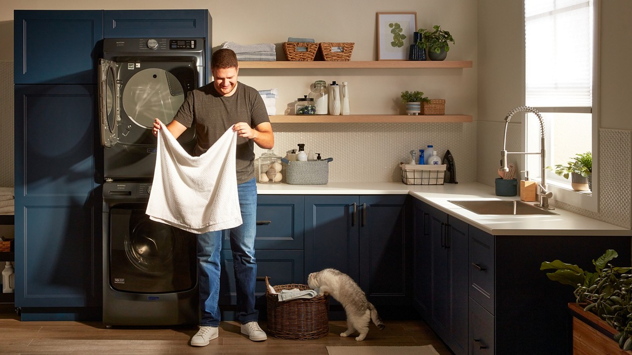 Une personne fait la lessive avec un ensemble laveuse et sécheuse à chargement frontal Maytag®