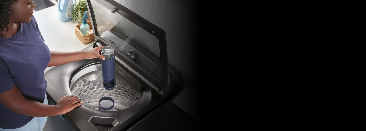 Une personne tient le filtre Pet Pro d’une laveuse Maytag®
