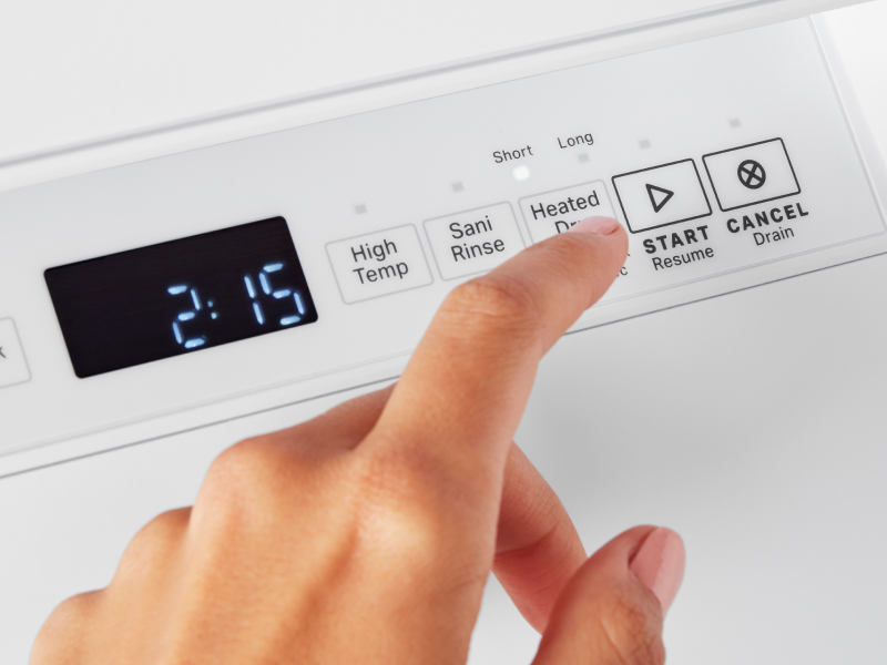 Person pushing start on white dishwasher.