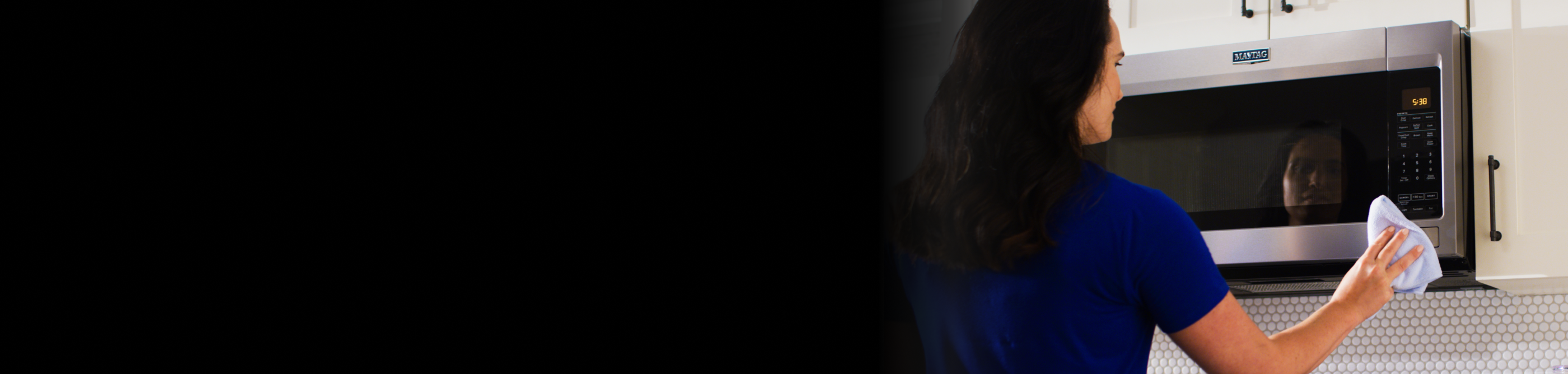 Woman wiping a Maytag® microwave
