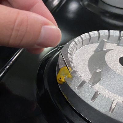 Removing cheese from burners with a needle