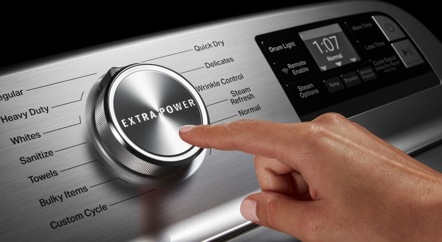 Un doigt sur le point d'appuyer sur le bouton « EXTRA POWER » d'une laveuse Maytag.