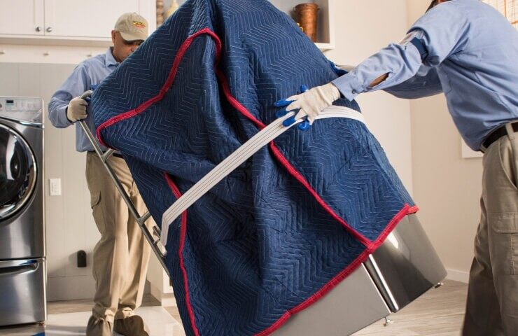 Deux personnes installent un nouvel appareil de lessive dans une salle de lavage.