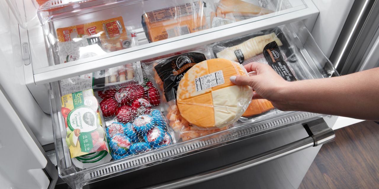 Hand removing cheese from a deli drawer. 