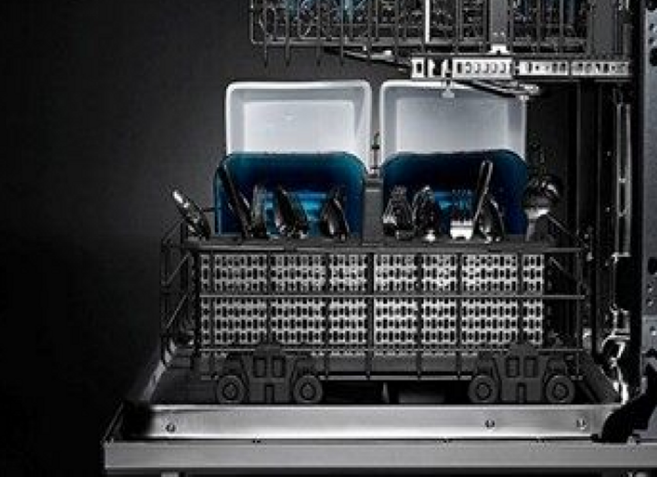 The lower rack of a dishwasher loaded with dishes and silverware.