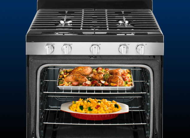 An oven cooking roasted chicken and a casserole.