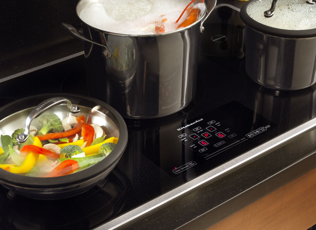 Pots and pans cooking food on an induction cooktop.