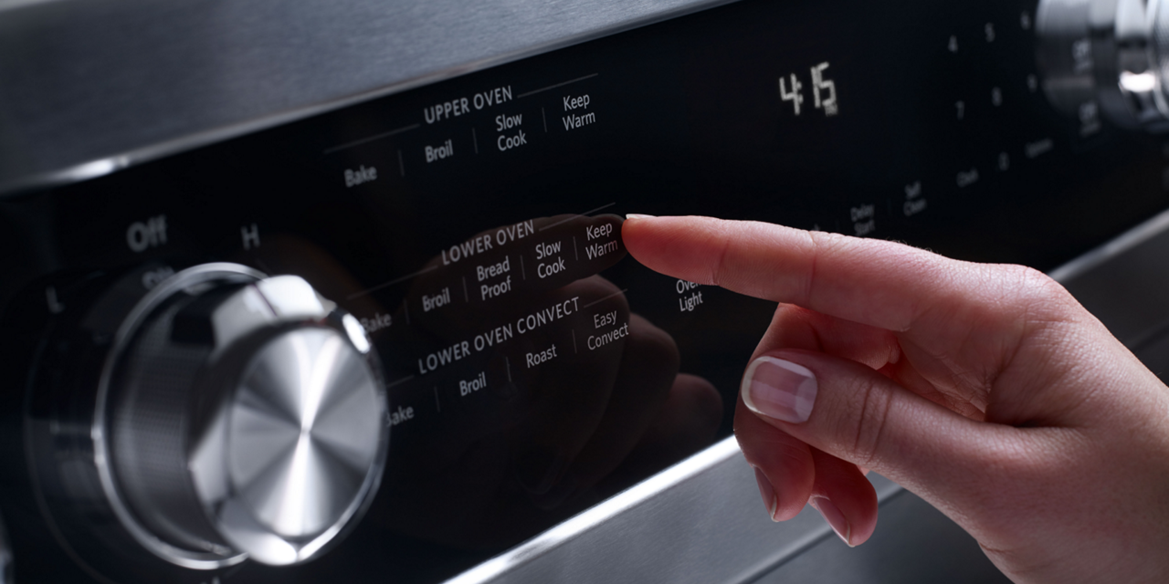 A person selects an oven setting from a range's control panel. A person selects an oven setting from a range's control panel.