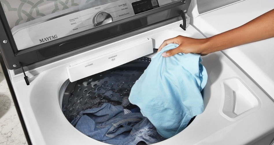 Women placing clothing items into a washing machine