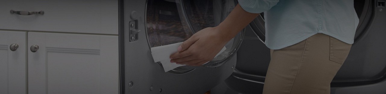 A woman cleaning the inside of a Maytag® front-load washer.