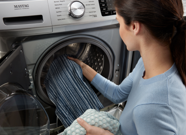 Woman loading laundry into a front load washer.