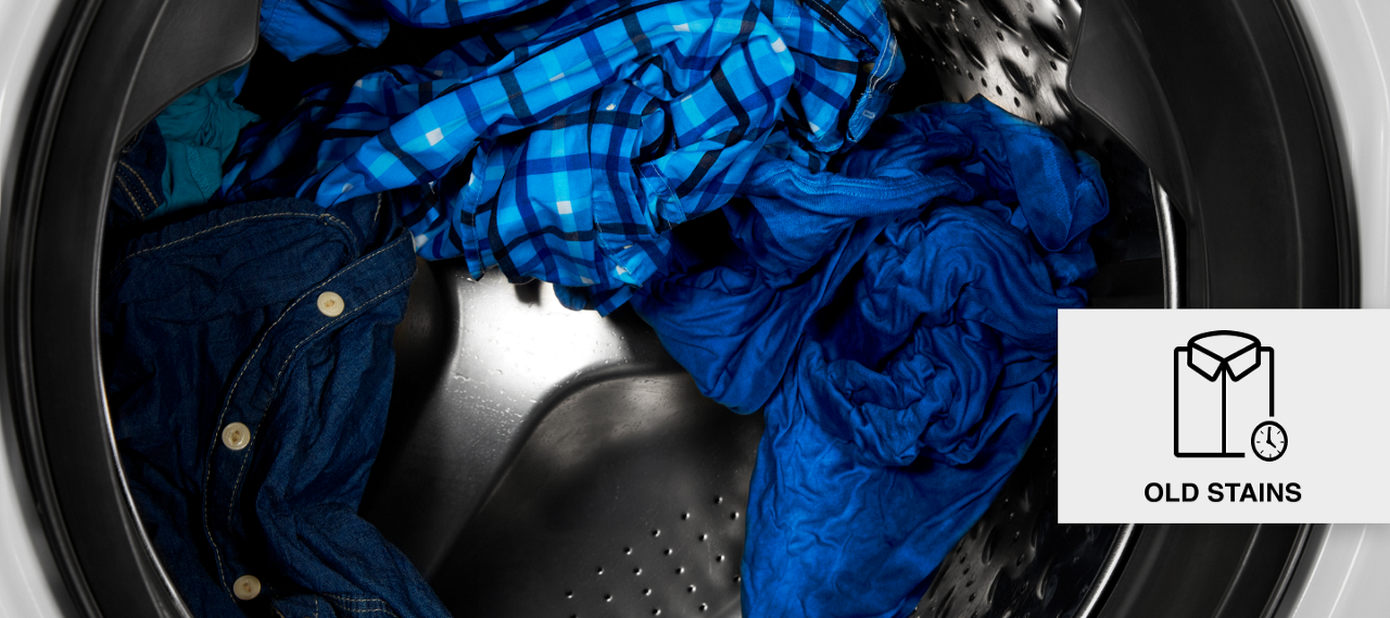 Blue clothes tumbling in a front load washer. Blue clothes tumbling in a front load washer.