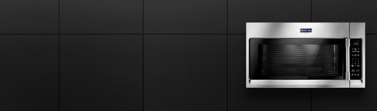 A stainless steel Maytag microwave against a black background.