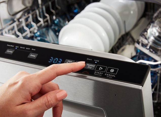 Main choisissant une option sur une console de lave-vaisselle 