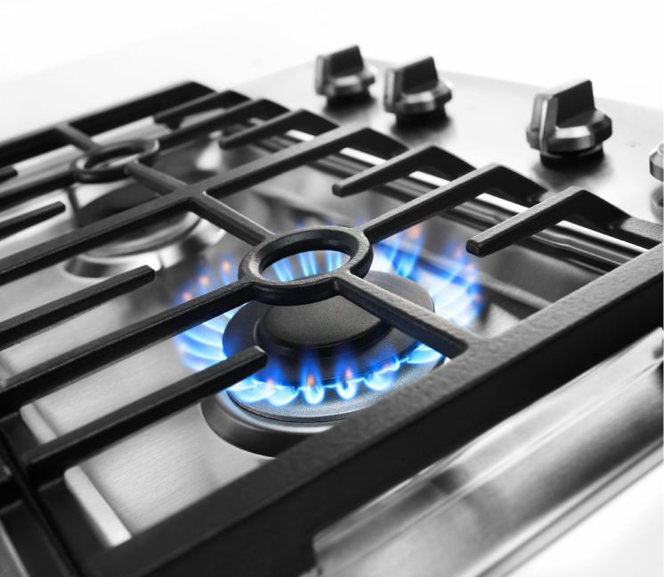 Une surface de cuisson au gaz avec une flamme de brûleur sur haute puissance.