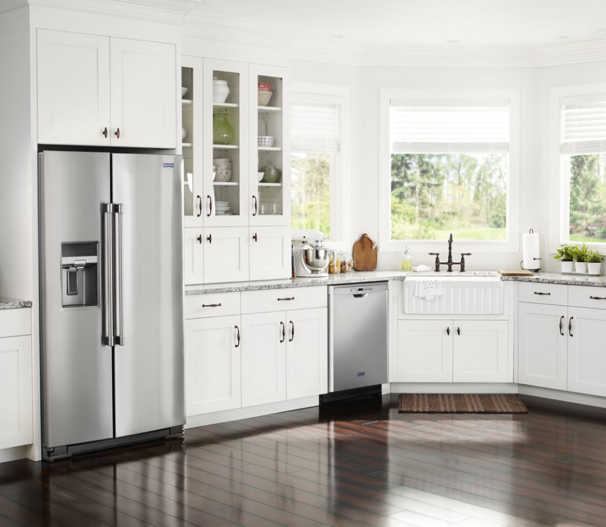 A counter-depth refrigerator placed inside a cabinet cutout.