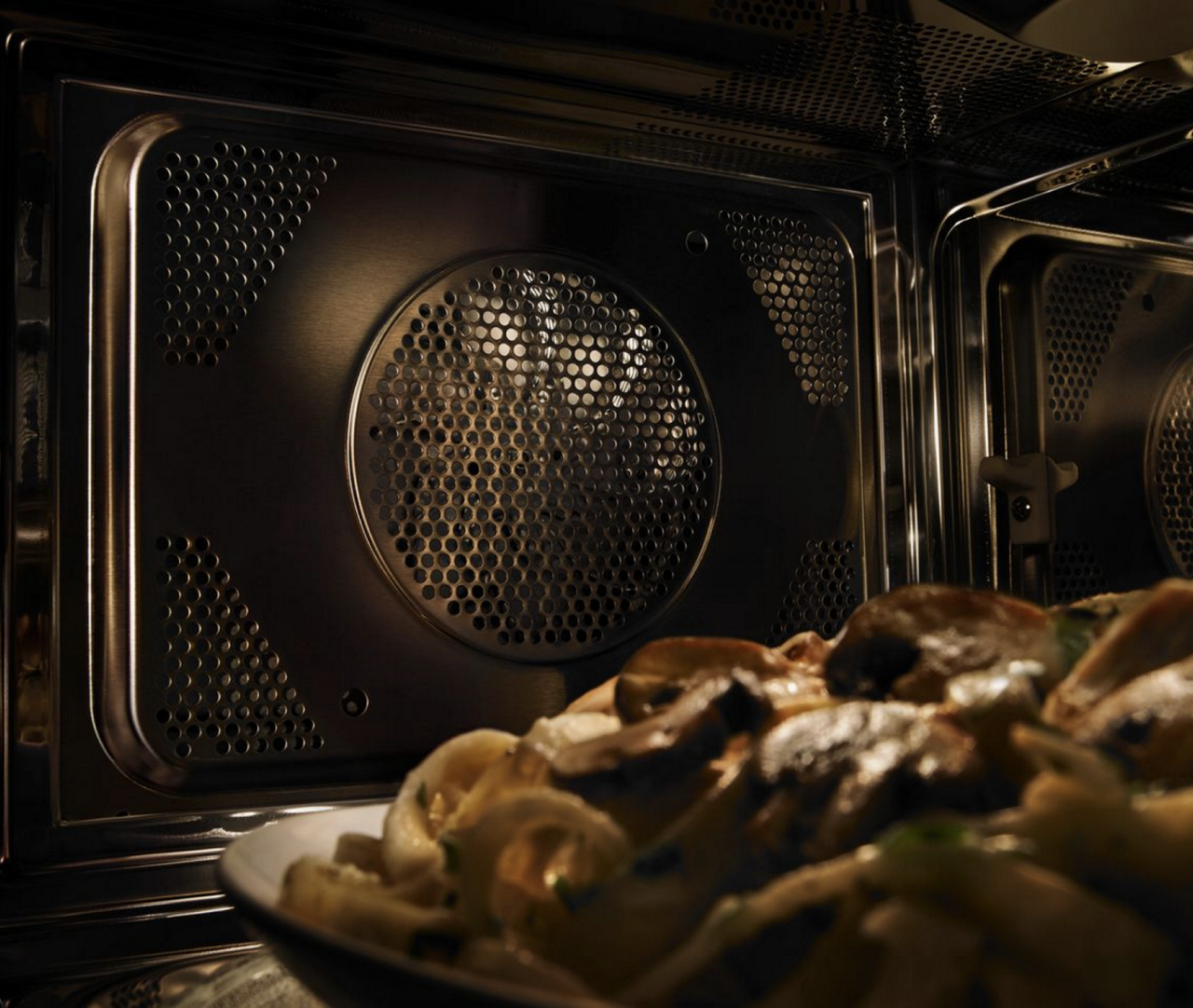 Gros plan d'un four à micro-ondes et convection Maytag avec une assiette de pâtes. 