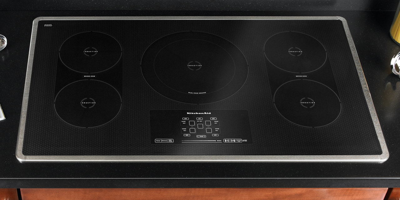 A black five burner induction cooktop with touchpad controls installed in a countertop.