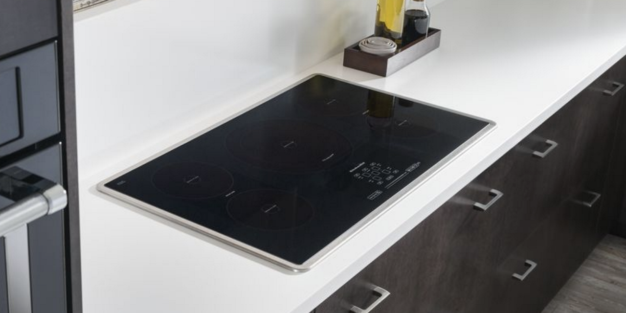 A black induction cooktop installed in a white countertop.