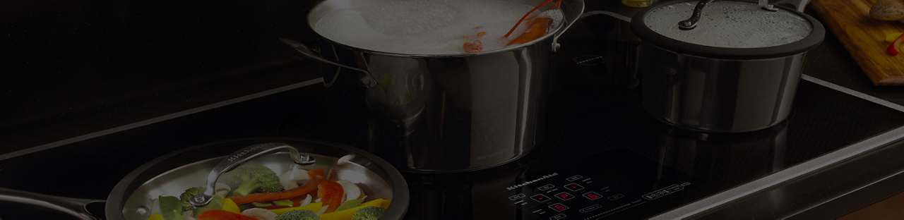 Casseroles et poêles remplies d’aliments cuisant sur une surface à induction