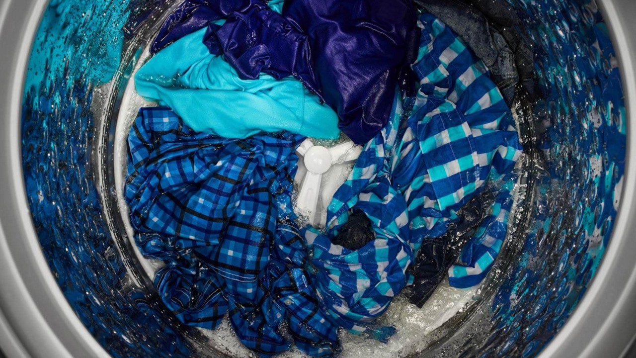 Laveuse à chargement vertical Maytag® remplie de vêtements bleus.