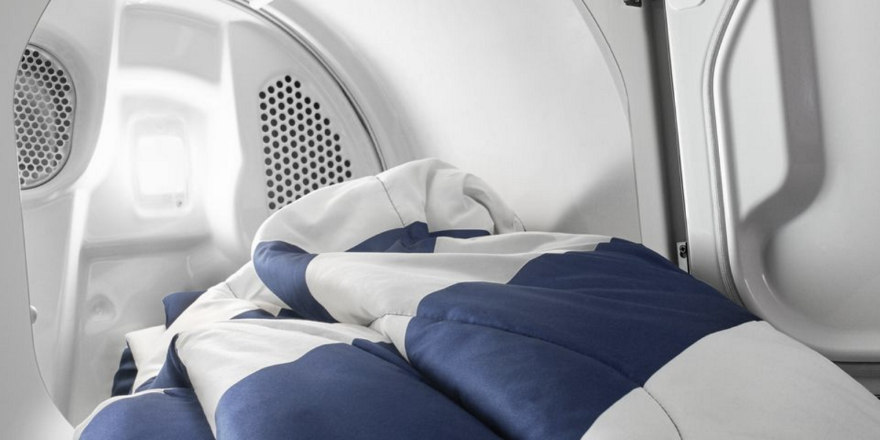 Une sécheuse Maytag ouverte avec une couverture qui en sort