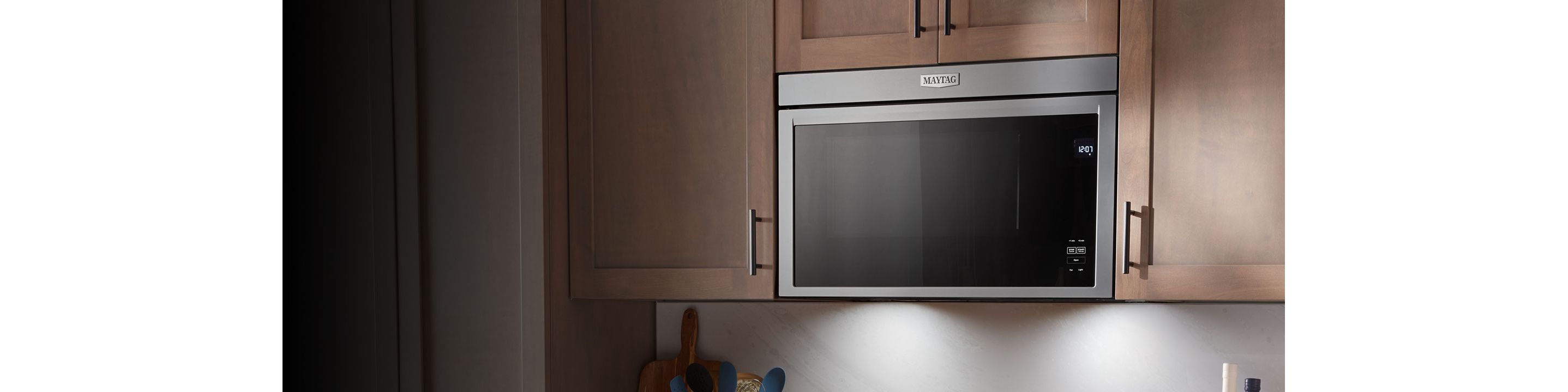 A stainless steel microwave against a dark background.