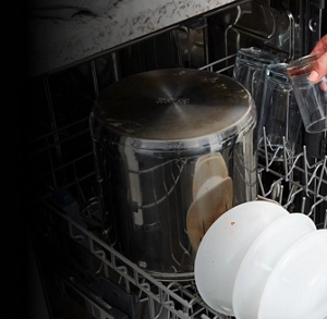  A metal stock pot and other dirty dishes loaded in a dishwasher rack 