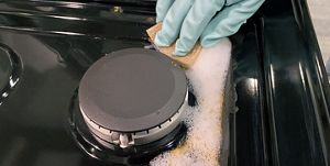 Cleaning a gas stove range top with grates and burners removed