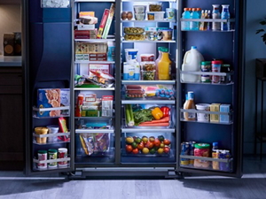 An open refrigerator full of food as well as full crisper drawers